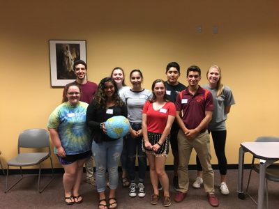 A group photo of students posing with smiles and a blue globe.