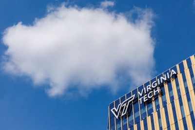 a blue and yellow Virginia Tech building and a clear blue sky with a large white puffy cloud